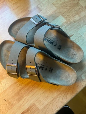 Grå Birkenstocks - Stilrena grå sandaler från Birkenstock med två breda remmar och justerbara metallspännen. Dessa passade inte mig i storleken och de är därför jag säljer dem, helt nya använda en gång utomhus. 
