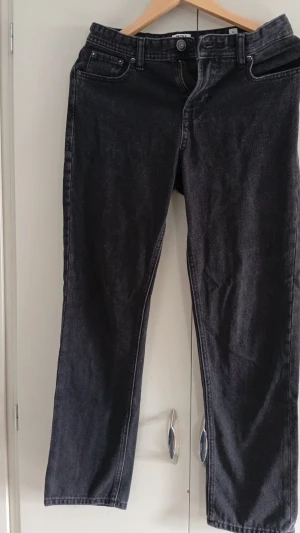 Jeans fån jack & Jones  - Säljer ett par svarta jeans från Jack & Jones med rak passform och klassisk femficksdesign. Jeansen har normal midja och är tillverkade i denim med lätt tvättad look. Perfekta för en stilren och avslappnad outfit. Säljs eftersom de inte används.