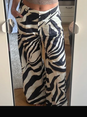 Zebramönstrade linnebyxor - Snygga linnebyxor med zebramönster och vida ben. Byxorna har hög midja och fickor i sidorna. Aldrig använda! Passar långa ben. Jag själv är 169 cm. 
