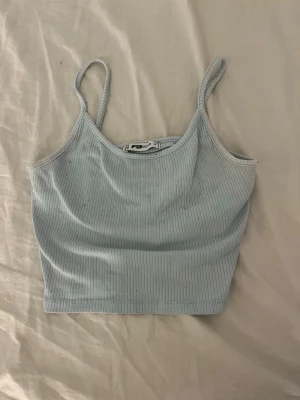 Ljusblå ribbad linnetopp från Sister S - Supersöt ljusblå ribbad linnetopp från Sister S med smala axelband och croppad passform. Perfekt att styla med jeans eller kjol för en chill look. Tunt och mjukt material som känns skönt mot huden.