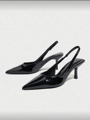 Svarta lackpumps med smal klack - Säljer ett par svarta pumps i glansigt lackmaterial med spetsig tå och smal, låg klack. Skorna har öppen häl och justerbar rem runt ankeln för en snygg och modern look. Perfekta för dig som gillar stilrena och trendiga skor. Säljer då dom var förstora när de köptes så helt nytt skick aldrig använda.