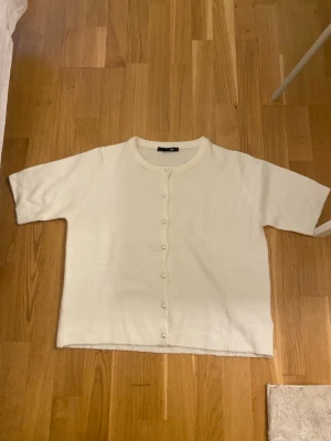 Vit kofta med pärlknappar - Kortärmad vit kofta med pärlknappar framtill. 