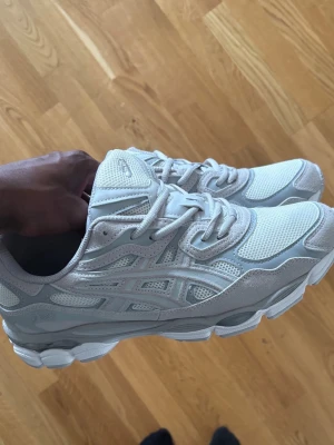 Vita Asics sneakers i mesh och mocka - Snygga vita sneakers från Asics med ovandel i mesh och detaljer i mocka. Skorna har en chunky sula och klassisk Asics-logga på sidan. Perfekta för dig som gillar stilrena och sportiga sneakers med modern vibe.