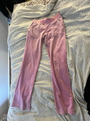 Rosa juicy byxor  - Säljer ett par rosa mjukisbyxor i mjuk velour med raka ben och stora fickor både fram och bak. Byxorna har en relaxed fit och bred linning, perfekta för en chill och avslappnad stil.