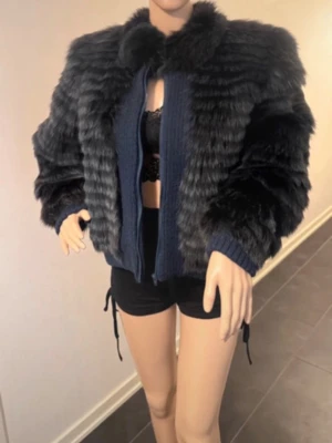 Svart kort pälsjacka med krage - Säljer en svart, fluffig pälsjacka i kort modell med bred krage och ribbade muddar. Jackan har en cool struktur med horisontella ränder och stängs framtill. Perfekt för dig som vill ha en statementjacka till höst och vinter.