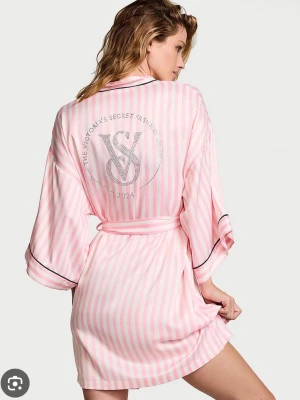 Rosa randig morgonrock Victoria's Secret - Säljer en rosa och vit randig morgonrock från Victoria's Secret med glittrig VS-logga och text på ryggen. Inte använts någon gång. 