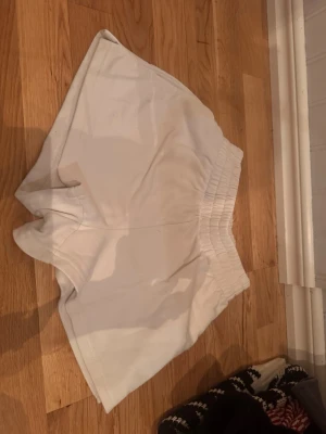 Vita loose shorts med resårmidja - Snygga vita shorts med bred resår i midjan och avslappnad passform. Perfekta för varma dagar och enkel att matcha med olika toppar. Tillverkade i mjukt material för extra komfort.