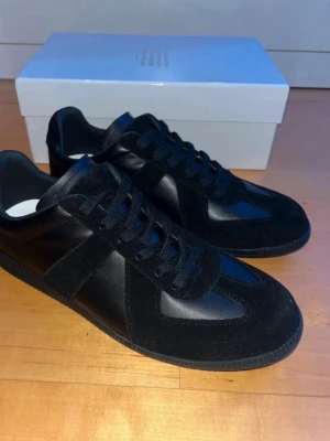 Svarta ”gat” sneakers från Maison Margiela - Skitsnygga svarta sneakers från Maison Margiela i läder, mocka och gummi. Storlek 47 men sitter mer som 45/46. Skriv vid minsta fundering!!
