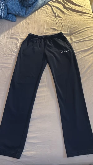Svarta mjukisbyxor från Champion XL - Säljer ett par svarta mjukisbyxor från Champion i storlek XL. Byxorna har resår i midjan och ett broderat Champion-logo på vänster sida. Tillverkade i ett mjukt och bekvämt material, perfekta för chill dagar eller träning.