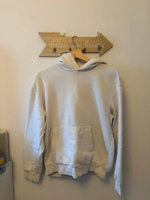 Beige hoodie med magficka - En stilren beige hoodie med stor magficka och luva, köpt från H&M. Perfekt för en avslappnad och enkel look. Materialet känns mjukt och bekvämt, troligen bomullsblandning.