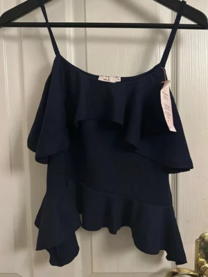 Volang Topp - Mörkblå volang topp från Nelly, oanvänd! Prislappen är kvar. 