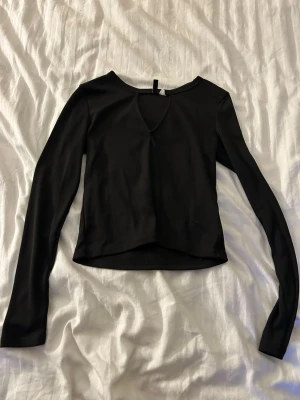 Svart långärmad topp från Gina Tricot - Säljer en svart långärmad topp från Gina Tricot med v-ringad detalj framtill.