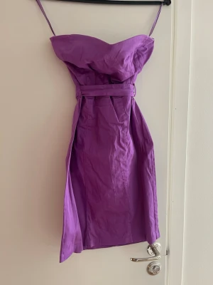 Lila axelbandslös kort klänning - Lila kort klänning utan axelband och bälte i midjan. Stretchigt material. 