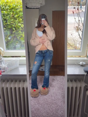 Ltb jeans - Säljer ett par blå bootcut jeans med slitningar och hål på ena låret. Jeansen har klassisk femficksdesign och låg midja. Perfekta för en avslappnad och trendig look.