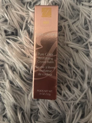 Estée Lauder Pure Color Crystal Balm - Säljer ett Estée Lauder Pure Color Revitalizing Crystal Balm i nyansen 004. Förpackningen är lyxigt roséguldig och balmet ger en återfuktande känsla till läpparna. Innehåller 3,2g och har en elegant, modern design.