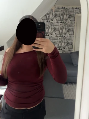 Mörkröd långärmad topp - Snygg mörkröd långärmad topp med figurnära passform och rund halsringning. Perfekt att styla med jeans eller kjol för en trendig look. Enkel och stilren design utan synliga detaljer.