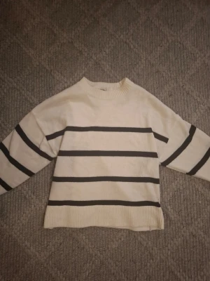Vit stickad tröja med svarta ränder - Vit stickad tröja med svarta horisontella ränder. Tröjan har rund halsringning, långa ärmar och ribbade muddar vid ärmslut och nederkant. Perfekt för en avslappnad och trendig look. Pris kan diskuteras ❤️❤️
