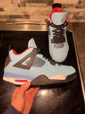 Air Jordan 4 x Travis Scott blå sneakers - Air Jordan 4 Travis Scott – Storlek 44  Säljer ett par riktigt snygga sneakers i mycket bra skick.   Populär modell med blå färg och röda/svarta detaljer som sticker ut. Passar perfekt till streetwear och är väldigt bekväma.  • Storlek: 44   • Skick: Mycket bra   • Väldigt efterfrågad modell     2000 kr (priset kan diskuteras vid snabb affär) Kan även kombineras med LV skorna för 2500 kr det vill säga 1250 kr per par skor.  Skriv gärna om du har frågor eller vill ha fler bilder!