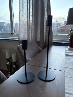 Svarta ljusstakar från Mio - Två stilrena ljusstakar i svart metall med rund fot och smal, hög design. Perfekta som dekoration på matbord eller hylla för ett modernt och enkelt uttryck. Passar vanliga kronljus och ger en snygg kontrast till ljusa inredningsdetaljer.