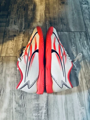 Vita och röda inomhus fotbollsskor Puma - Säljer ett par snygga fotbollsskor från Puma med vit mesh och röda detaljer. Skorna har svarta grafiska linjer och en cool design som sticker ut. Yttersulan är röd och insidan har en matchande röd färg. 