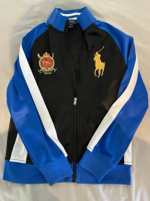Polo Ralph Lauren tröja (äkta) - Äkta Polo Ralph Lauren-tröja i storlek 164, motsvarande 14–16 år. Klassisk design med Ralph Lauren-logga på bröstet. Perfekt för vardagen då den tröja har bra skick. Modell 177 cm och bär 170 eller (xs).