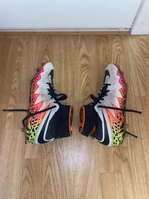 Nike Hypervenom Phantom II FG - Säljer ett par Nike Hypervenom Phantom II FG fotbollsskor med högt skaft och snörning. Skorna har en grym färgkombination i vitt, svart, orange, rosa och neongult med grafiskt mönster. Tillverkade i syntetmaterial för bra grepp och känsla på planen. Storlek 40,5. Pris kan diskuteras 