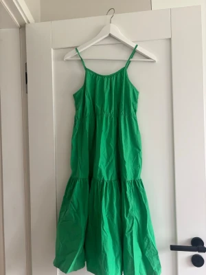 Grön sommarklänning från Zara - Säljer en grön klänning med smala axelband och voluminös kjol. Mycket bra skick och knappt använd. Storleken är 13-14 år med passar allt från xss-S