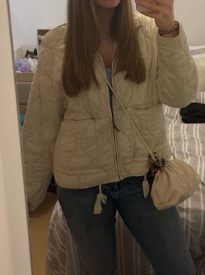 Beige quiltad jacka från Zara  - Jättesnygg trendig beige quiltad jacka med snörning i midjan och dragkedja framtill. Jackan har en avslappnad passform och långa ärmar. Perfekt till våren, i mycket bra skick, skriv för fler bilder!🫰🩵