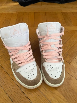 Nike Air Jordan 1  - Säljer ett par Nike Air Jordan 1 Mid sneakers i vit och rosa mocka men den har blivit missfärgade efter tvätten men annars är den i bra sick och riktiga du får med Jordan låda ( priset går att diskutera) // nytt pris runt 2200 kr 🩷