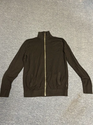 Svart ziptröja cardigan - Snygg svart ziptröja med hel dragkedja och hög krage. Tröjan har långa ärmar, ribbade muddar och två fickor framtill. Perfekt för lager-på-lager och enkel att matcha med andra plagg.