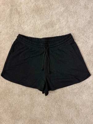 Mörkgråa shorts med snörning - Mjuka shorts med elastisk midja och snörning framtill. Perfekta för chill dagar eller träning. Tillverkade i ett bekvämt bomullsmaterial och har en enkel, loose passform.