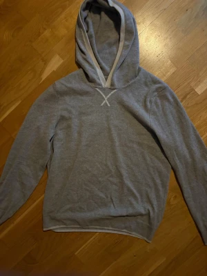 Grå Kashmir hoodie från falconeri - En stilren grå hoodie med huva och en snygg X-detalj vid halsringningen.  100% puro cashmere. Orginal pris 2600kr och denna färg finns inte på hemsidan längre. 