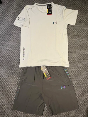 Under Armour set - Snyggt grå träningsset från Under Armour med t-shirt och shorts. Perfekt som träningskläder men också till sommaren. Storleken är L men den passar perfekt som S-M. Ifall ni har några funderingar så är det bara att fråga