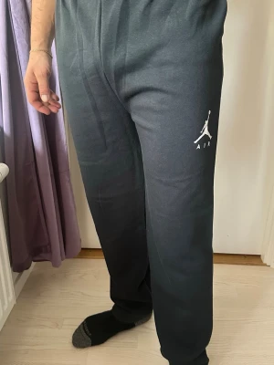 Svarta Jordan mjukisbyxor med logga - Säljer ett par svarta mjukisbyxor från Jordan med den klassiska vita Jumpman-loggan och texten AIR på vänster ben. Byxorna har avslappnad passform och resår i midjan. Perfekta för chill eller träning.