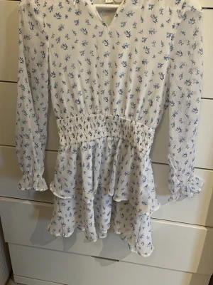 Söt sommar klänning!  - En snygg vit volang klänning med små blåa blommor på, den har scrunch i midjan, (stretchig) och är luftig och skön. Lite genomskinlig men inget som märks, perfekt till sommaren eller en avslutning/student 💕ALDRIG ANVÄND! (strl 152) passar till xxs-xs