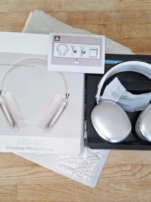 MS-B1 trådlösa hörlurar silver - Snygga trådlösa over-ear hörlurar i silver med modern design. Hörlurarna har en vadderad huvudbygel och stora, ovala kåpor i metall-look. Perfekta för musik, gaming eller videos. Levereras i originalförpackning med instruktioner.