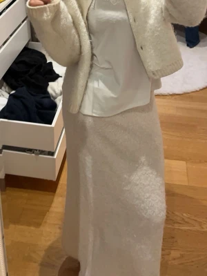 Vit långkjol i fleece från Kappahl - Mysig vit långkjol från Kappahl i mjukt fleecematerial. Kjolen har en rak och enkel design med bred linning och passar perfekt för kalla dagar. Superbekväm och lätt att matcha med olika toppar.