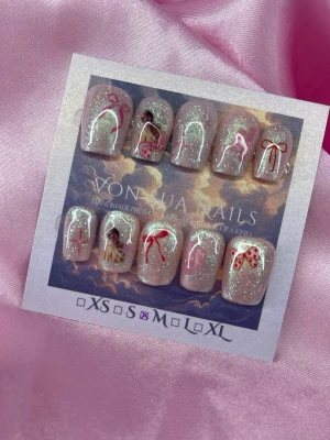 April (M);Short Ballerina - Handgjorda press-on naglar med skimrande, ljusrosa bas och detaljer som röda och rosa rosetter, små bilder och vita bågar. Naglarna har en söt och lekfull design med glittereffekt och olika motiv på varje nagel. Perfekt för dig som vill ha unika och kreativa naglar.