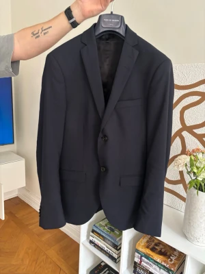 Tiger of Sweden - Mörkblå kostym från Tiger of Sweden som använts en gång vid min student 2024. Alla delar är i nyskick, finns inga märken eller liknande som tyder på användning.  Storlek 44 på alla delar, kavaj, väst och byxor.   För fler bilder är det välkommet att skriva.  Finns att hämta och prova i Örebro. Frakt går att ordna mot köpares bekostnad :)