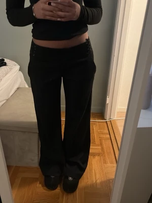 Svarta wide byxor med snörning - Säljer ett par svarta wide byxor från Clothes i storlek 38. Byxorna har låg midja och cool snörningsdetalj i sidorna vid linningen. 