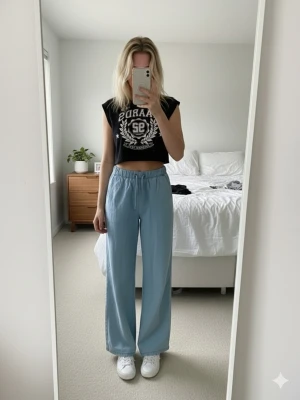 Svart croppad linnetopp FB Sister - Cool svart croppad linnetopp från FB Sister med vitt tryck framtill, texten 'RAIDS 92 NATIONAL PARK' och stjärndetaljer. Toppen har v-ringning och är ärmlös, perfekt till jeans eller shorts för en avslappnad look.