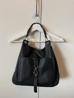 Svart väska med silverdetaljer - En handväska från Don Donna i bucket-modell. Endast använd enstaka gånger och är i nyskick. Förhoppningsvis kommer den till användning hos någon annan. Nypris 499kr💕