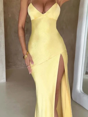 Gul långklänning med slits - Snygg gul långklänning i satinliknande material med smala axelband och v-ringad urringning. Klänningen har en hög slits på ena sidan som ger en trendig look. Perfekt för dig som vill sticka ut med en elegant och modern stil. Aldrig använt