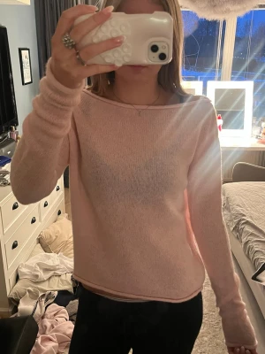 Ljusrosa stickad tröja - Säljer en ljusrosa stickad tröja med rund hals och långa ärmar. Tröjan har en enkel och avslappnad passform, perfekt för att slänga på sig till jeans eller leggings. Materialet är mjukt och tunt, vilket gör den skön att bära inomhus eller under en jacka.