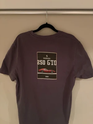 Grå Ferrari 250 GTO t-shirt - Snygg grå t-shirt med tryck av en röd Ferrari 250 GTO och texten '1962' på bröstet. T-shirten har klassisk passform och korta ärmar, perfekt för dig som gillar bilar och vill sticka ut med en unik design. Helt ny aldrig använt 