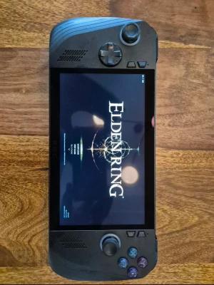 ASUS ROG Ally bärbar spelkonsol - Säljer en svart ASUS ROG Ally bärbar spelkonsol med stor skärm och inbyggda kontroller. Konsolen har en modern design med färgade knappar och texturerat grepp på baksidan. Perfekt för gaming på språng och stödjer populära spel som Elden Ring.