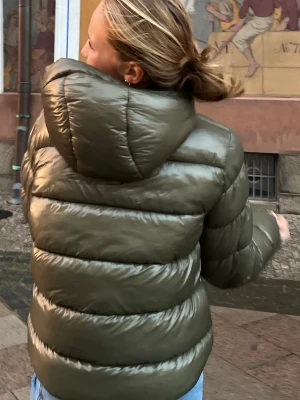 Olivgrön dunjacka - Säljer en olivgrön pufferjacka från superdry med glansigt material och stor huva. Jackan har dragkedja framtill och två sidofickor. Perfekt för kalla vinterdagar. Helt slutsåld!! Så snygg! Nypris 1500