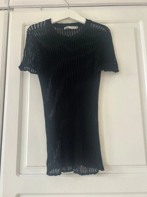 Svart ribbad topp från Zara💖💖✨ - Trendig svart ribbad topp från Zara med korta ärmar och rund hals. Toppen är genomskinlig och har en tight passform som framhäver siluetten. Perfekt att styla lager på lager eller med ett snyggt linne under.
