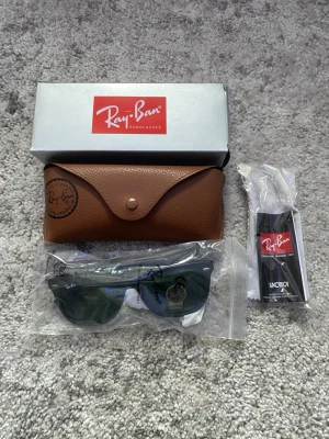 Ray-Ban Solglasögon - Ett par svarta Ray-Ban solglasögon i nytt skick, oanvända. Orginalförpackning, etui med mera medföljer självklart (se bild 5). Hör gärna av er om det är nåt ni undrar!