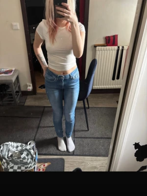 Blå skinny jeans med låg midja - Säljer ett par ljusblå skinny jeans med låg midja och klassisk femficksdesign. Jeansen har en tight passform och är perfekta för en avslappnad och trendig look. Materialet är stretchigt denim som sitter snyggt och bekvämt hela dagen.